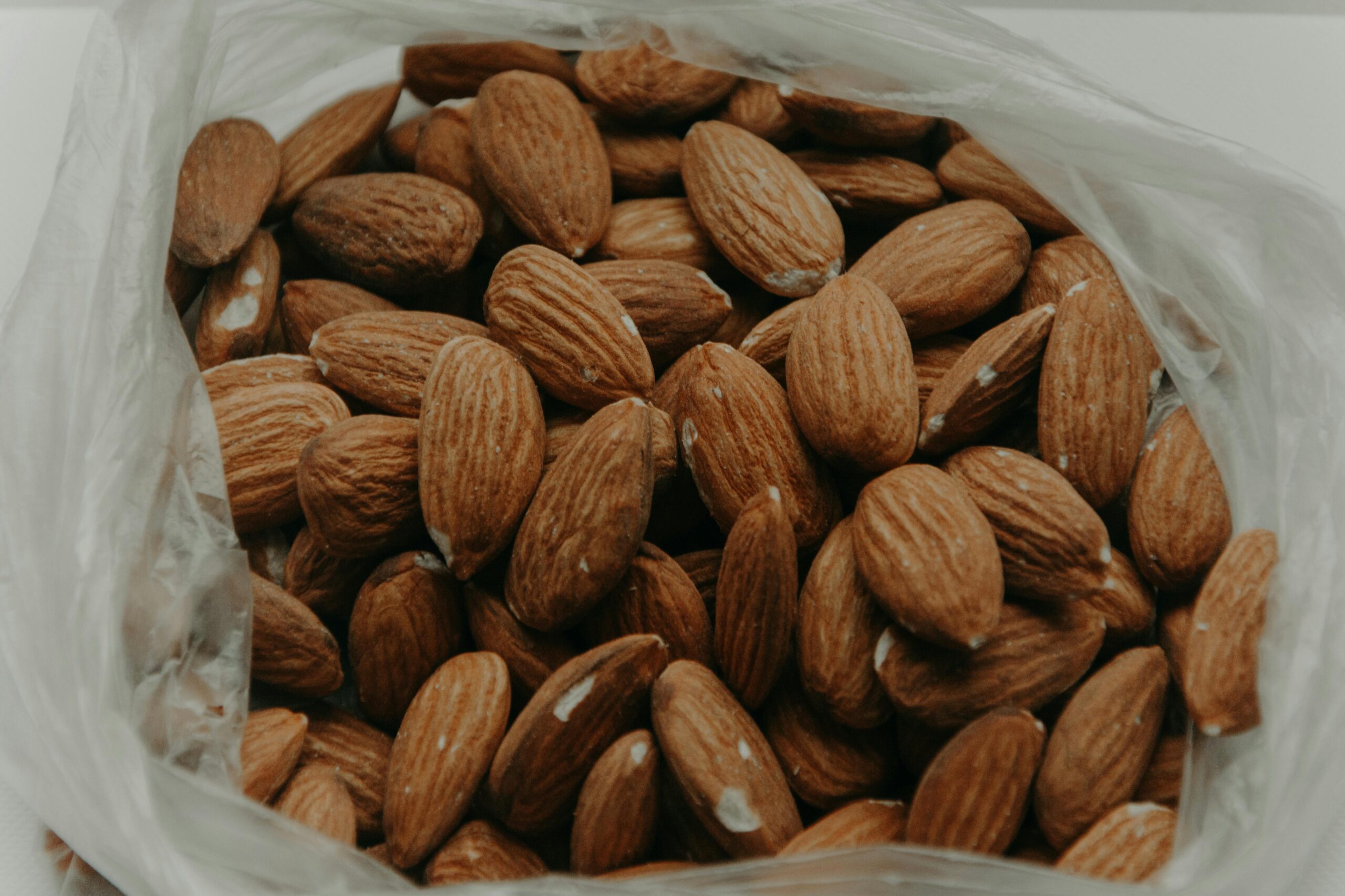 Close-up of raw almonds in a plastic bag, showcasing their texture and nutty appeal.