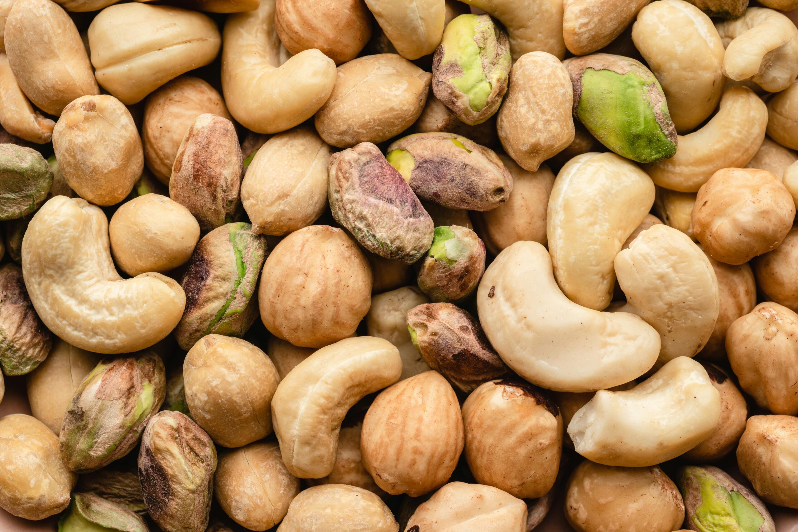 Detailed macro shot of assorted cashews and pistachios, showcasing texture and color